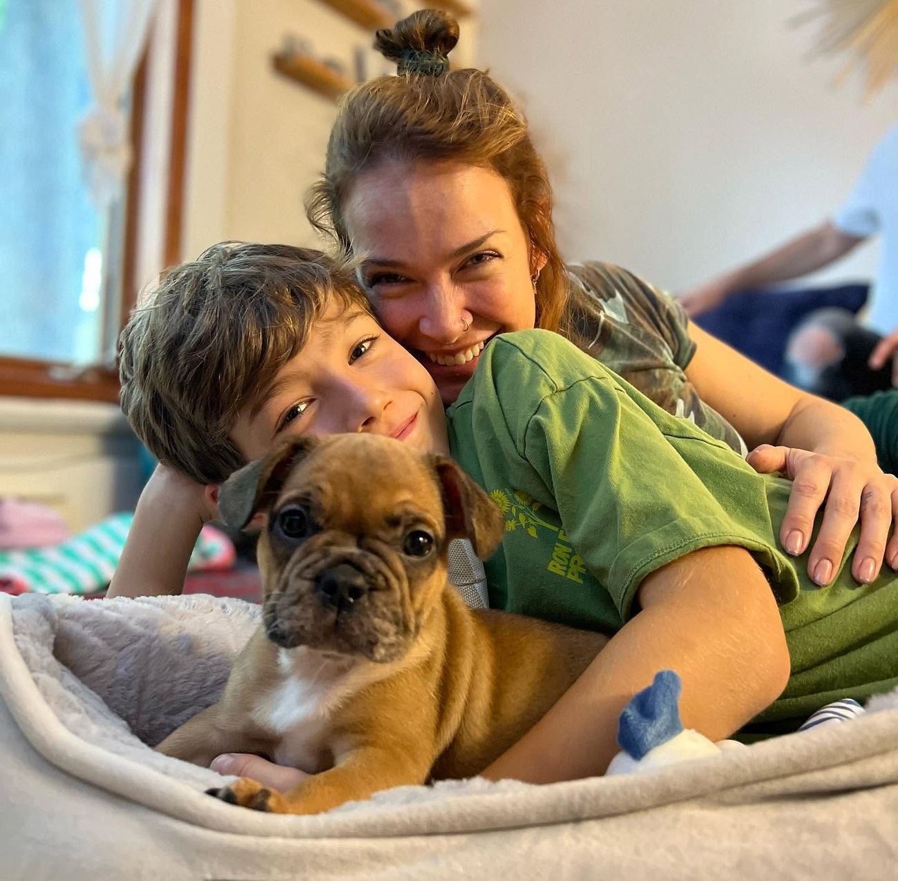 A mother and son cuddling their new Frenchie puppy